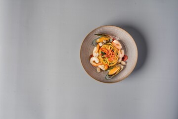 Top view of a bowl of pasta with shrimps on a gray background