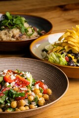 Vertical closeup of a bowl of salad with peas and tomato on a wooden table