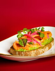 Closeup of salmon and avocado on a toast on a red background
