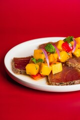 Closeup of steak slices with vegetables on a red background