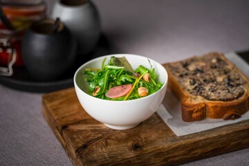 Closeup of a toast and a bowl of salad on a wooden cutting board