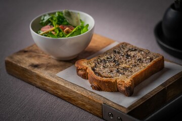 Closeup of a toast and a bowl of salad on a wooden cutting board