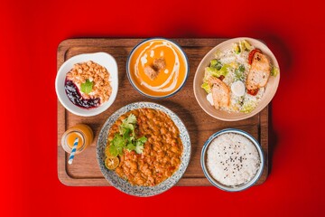 Top view of various dishes on a cutting board on a red background