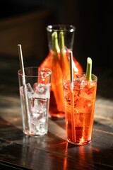 Closeup of glasses of cocktail with straw and ice cubes on a wooden table