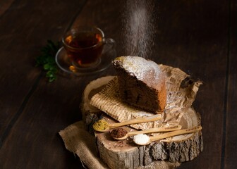 Freshly-baked slice of cake with spices on the wooden plate near the cup of hot tea