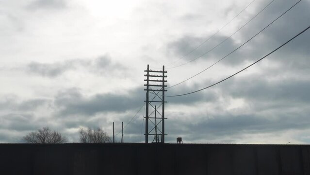 Time lapse footage of the dense clouds moving over a high-tension line open-wire pole