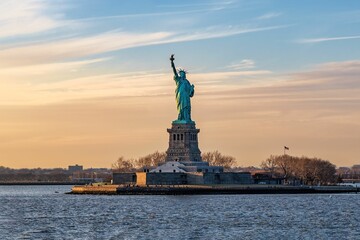 Fototapeta premium Breathtaking image of the iconic Statue of Liberty in New York City, USA under a stunning sunset sky
