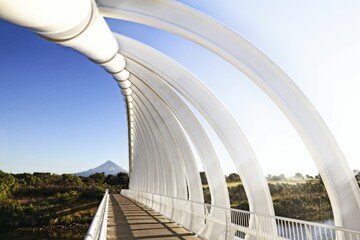 Te Rewa Rewa bridge with multiple white vertical poles on top of it, Mount Taranaki, New Zealand.