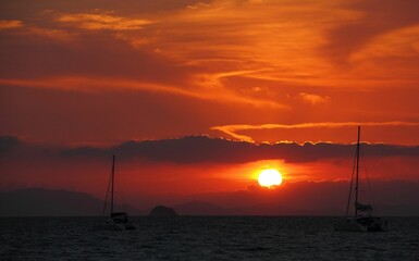 Scenic view of sailboats gliding across a tranquil body of water at sunset. Thailand, Railay Beach.