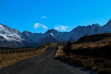 dirt road winding away with mountain range in background under blue sky