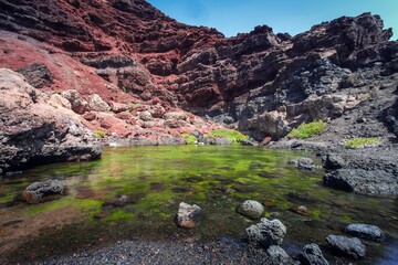 a body of water sitting between rocks and a mountain face