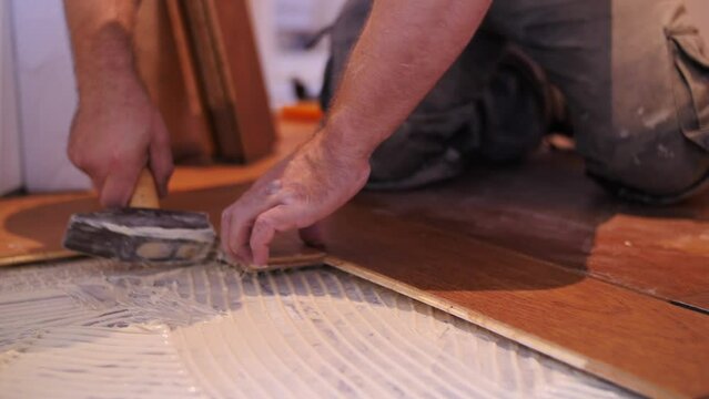 Slow motion Professional man hands parquet installation using hammer