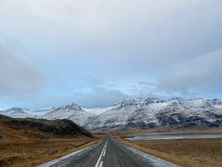 the long straight road in iceland with the mountains behind it