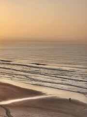 Sunset reflecting over the sea with people walking on the beach sand