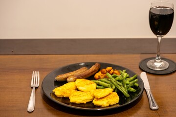 Nutritious meal of fresh vegetables and eggs served on a black plate, accompanied by a glass of wine