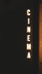 Illuminated cinema sign glowing brightly in the night, situated on the facade of a building.