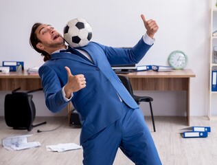 Young male employee playing football in the office