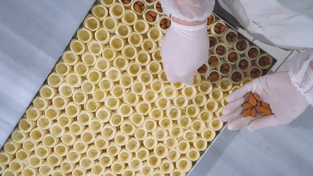 The chef of oriental sweets adds almonds to the dough to make Osh Al-Bulbul sweets