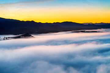 Cloud inversion over valley at sunrise, sunset, with mountains