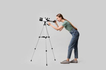 Young astronomer looking at stars through telescope on grey background