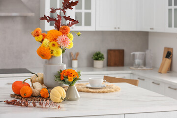 Beautiful autumn bouquets and pumpkins on marble table in kitchen