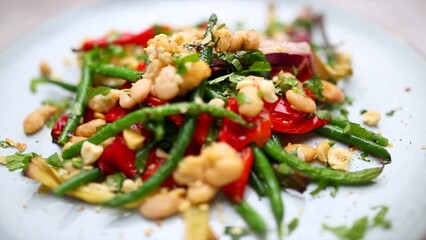 Mixed bean salad on a plate. Footage of white and green bean roasted salad. Shallow depth field footage of plant based vegetarian cooking.