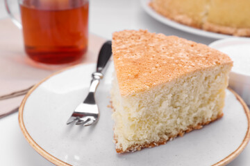 Piece of tasty sponge cake on white table, closeup