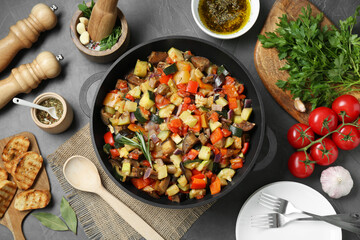 Delicious ratatouille and ingredients on grey table, flat lay