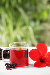 Delicious hibiscus tea and flowers on white wooden table outdoors, space for text
