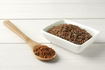 Caraway (Persian cumin) seeds and powder on white wooden table