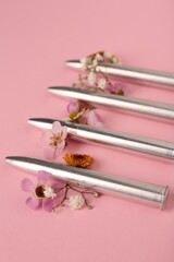 Metal bullets and beautiful flowers on pink background, closeup