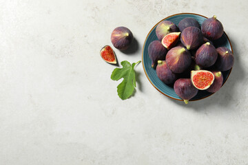 Plate with fresh ripe figs and green leaf on light table, flat lay. Space for text