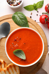 Delicious tomato soup served on white wooden table, flat lay