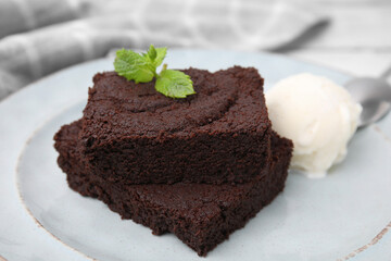 Tasty brownies served with ice cream and mint on table, closeup