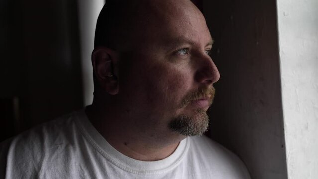 Serious looking man deep in thought and contemplation looking outside. Man with depression, anxiety and worry looking out window.