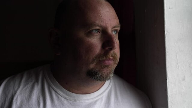 Serious looking man deep in thought and contemplation looking outside. Man with depression, anxiety and worry looking out window.