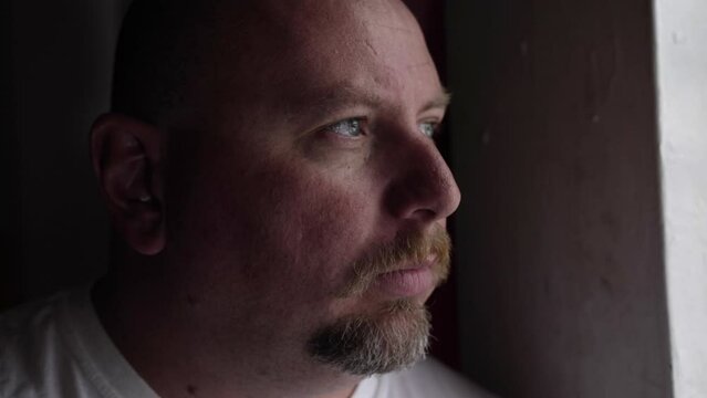 Serious looking man deep in thought and contemplation looking outside. Man with depression, anxiety and worry looking out window.
