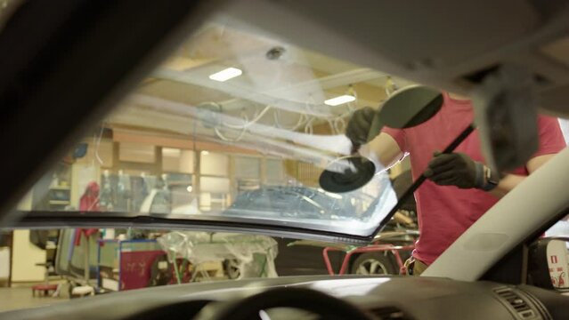 Workshop technicians use suction cups to remove cracked car windscreen