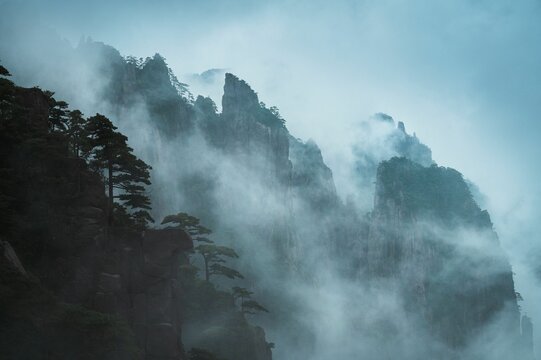 Breathtaking aerial view of majestic mountains with lush green treetops reaching towards the sky