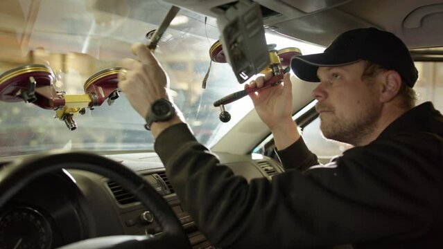 Repairman fastens suction cups to replace cracked windshield, side view