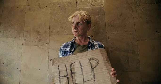 video of a woman beggar holding a sign saying help as they are stuck in life and not doing well mentally and physically.