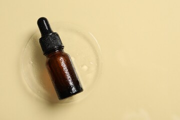 Bottle of cosmetic serum on beige background, top view. Space for text