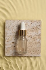 Bottle of cosmetic serum and water on beige background, top view