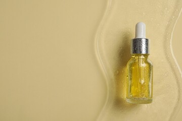 Bottle of cosmetic serum on beige background, top view. Space for text