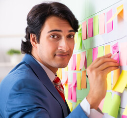 Young handsome employee with many conflicting priorities