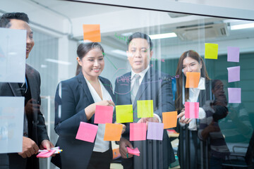 executives business asian entrepreneur of small company putting a adhesive note on glass in office...
