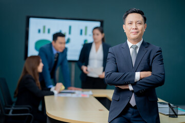 Handsome Asian middle-aged executives business man standing confident in the office in front of his team.