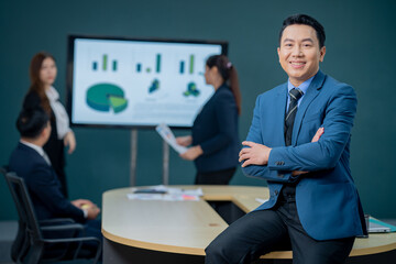 Handsome Asian middle-aged executives business man standing confident in the office in front of his team.