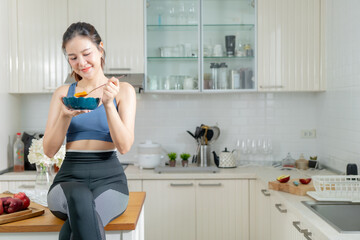 Healthy Asian woman in exercise clothes Is happily cooking a healthy meal in her home kitchen in...