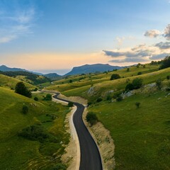 Aerial view of a mountain road in green hills at sunset